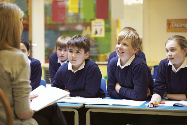 School children in a classroom looking towards a female teacher