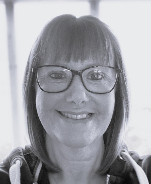 A black and white photo of a white woman smiling at the camera.