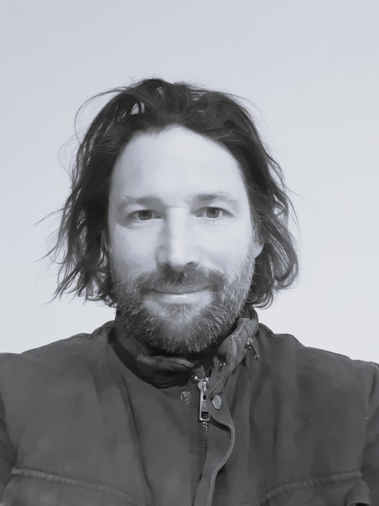 Black and white selfie of a man smiling at the camera