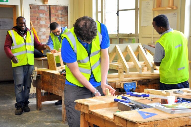 four learners wearing hi vis vests doing carpentry