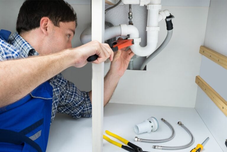 A plumber fixing below a sink