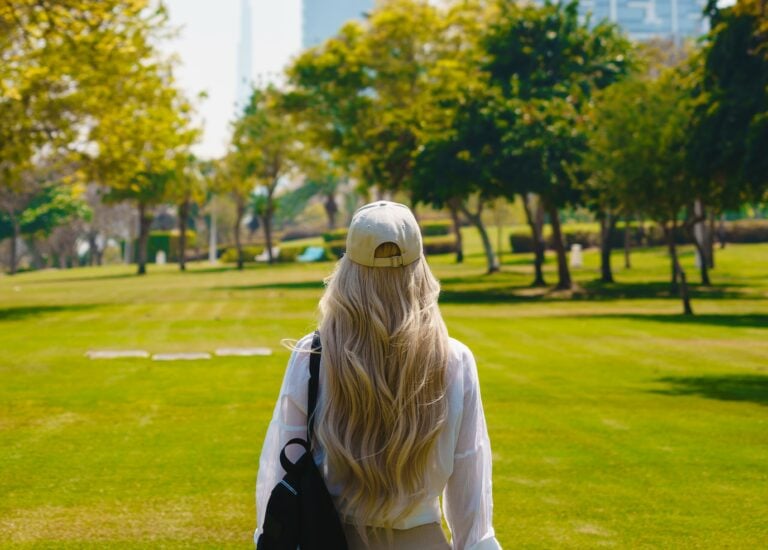 A woman with her back to us walking in a park with trees