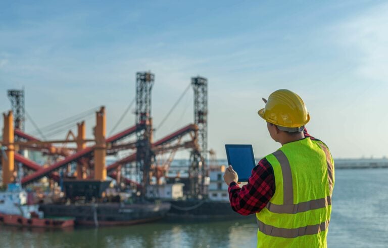 Man in a his vis vest looking out a shipping yard