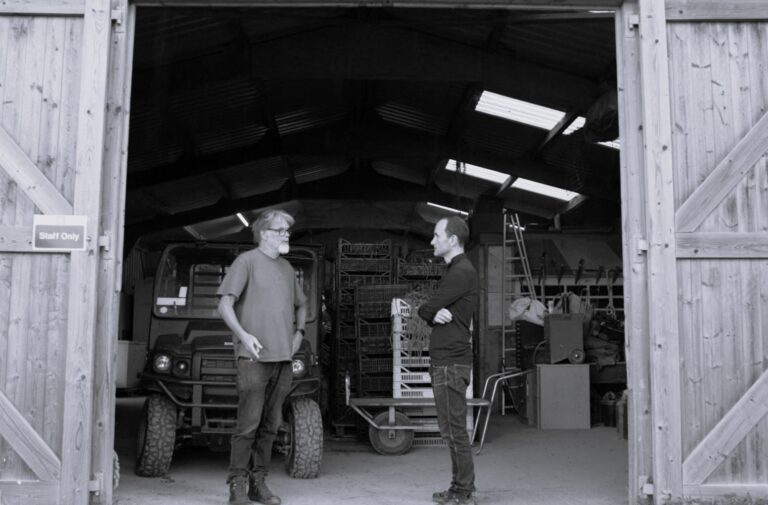 two men stood in a barn talking