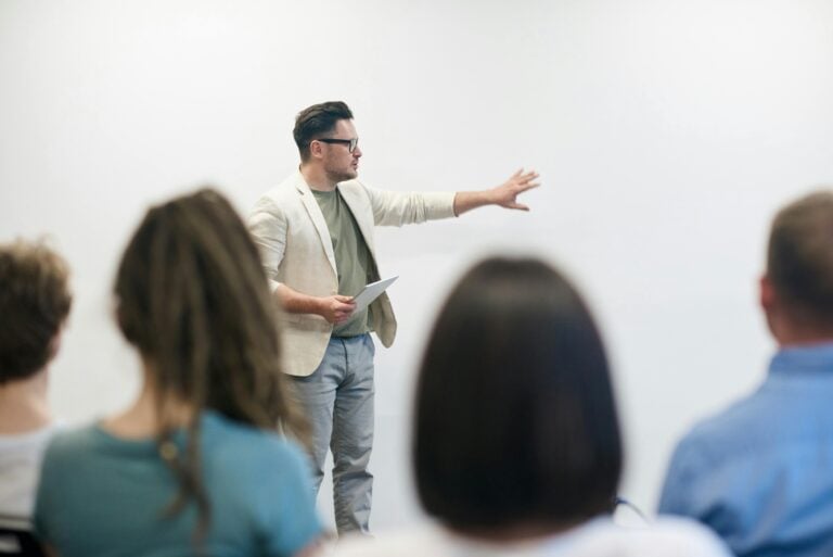 Man stood in front of a class of adult students, teaching