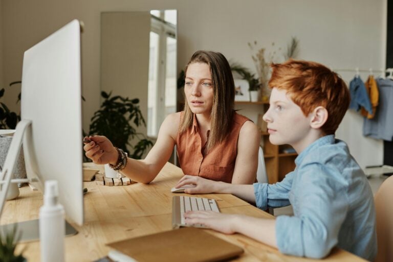 Teacher sat with a child looking at a computer